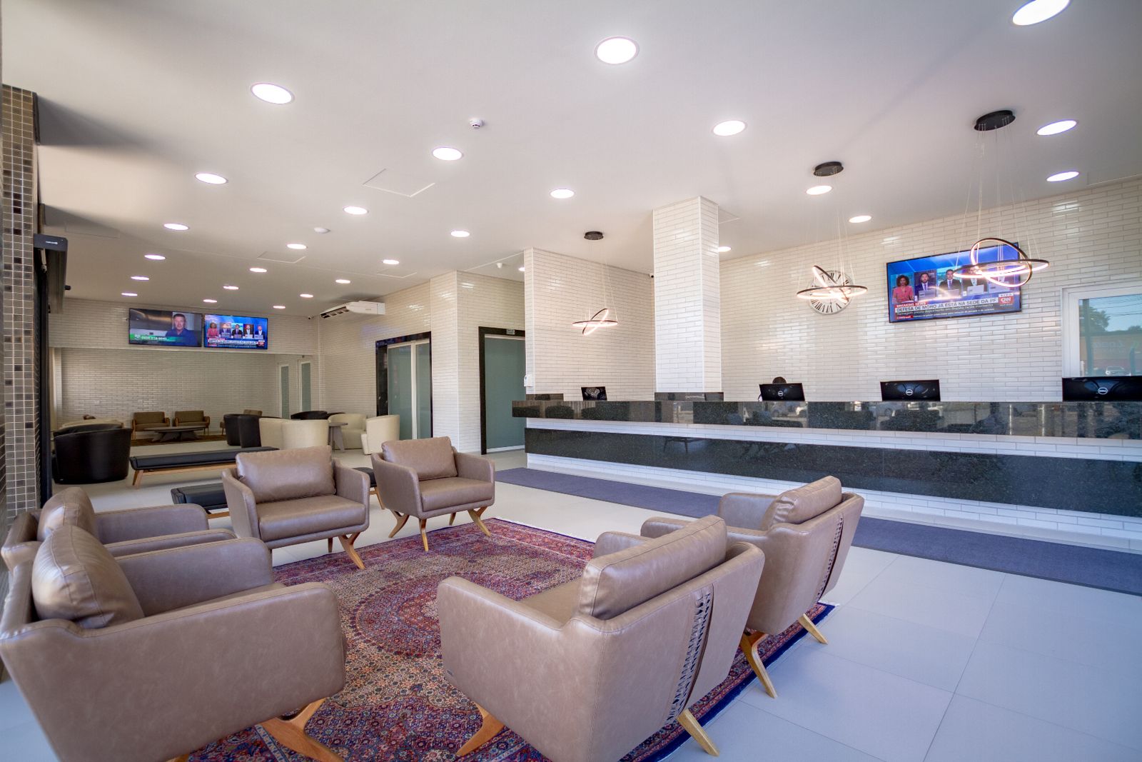 Lobby do Hotel Confiance Barigui com poltronas, tapete persa e balcão de recepção ao fundo